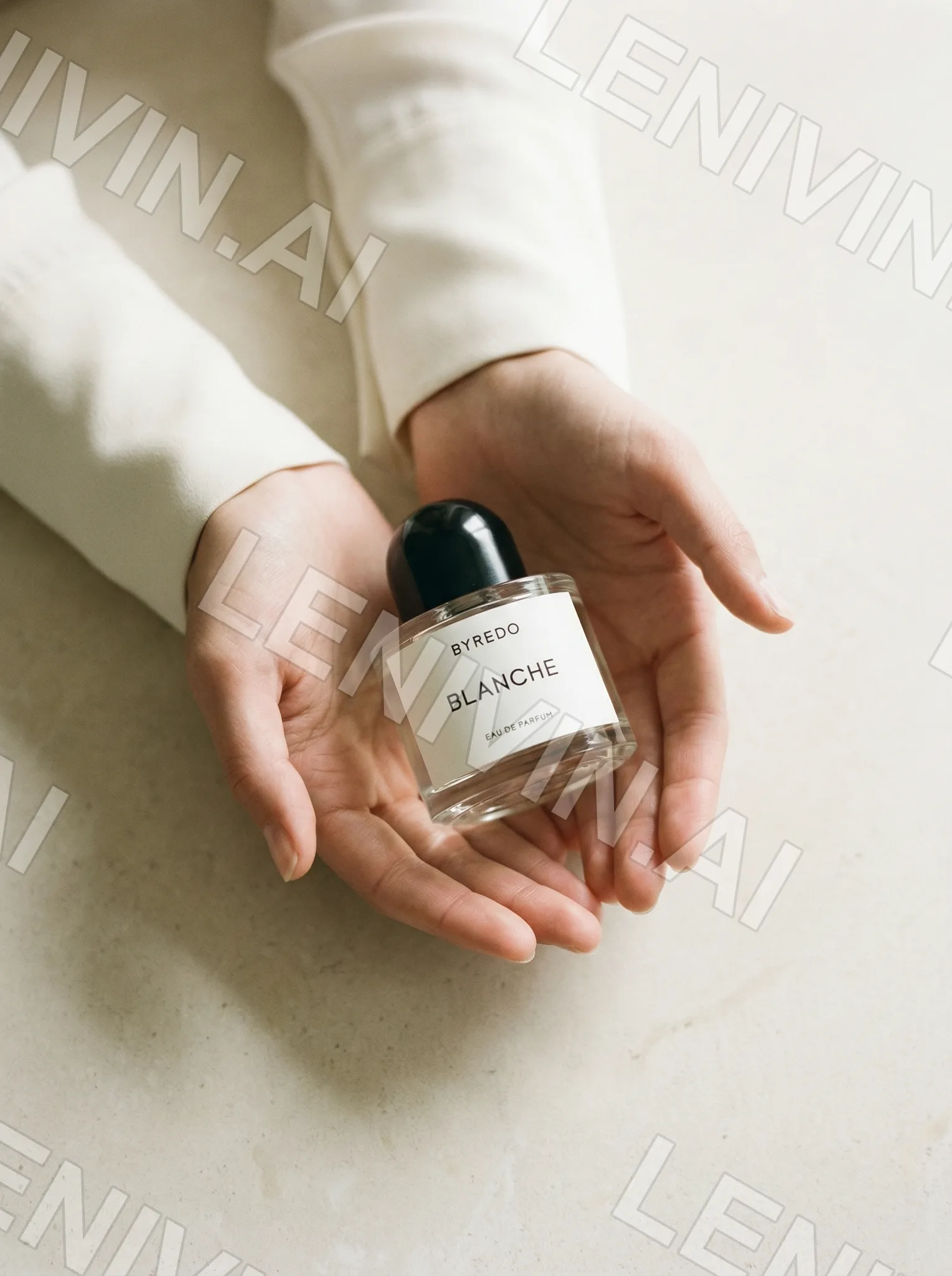 Ладони с флаконом парфюма BYREDO Blanche на светлом фоне