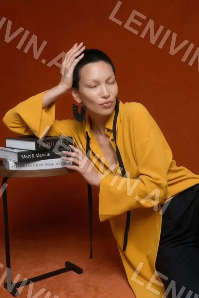 Ролик: женщина в жёлтой рубашке с книгами на столике на оранжевом фоне