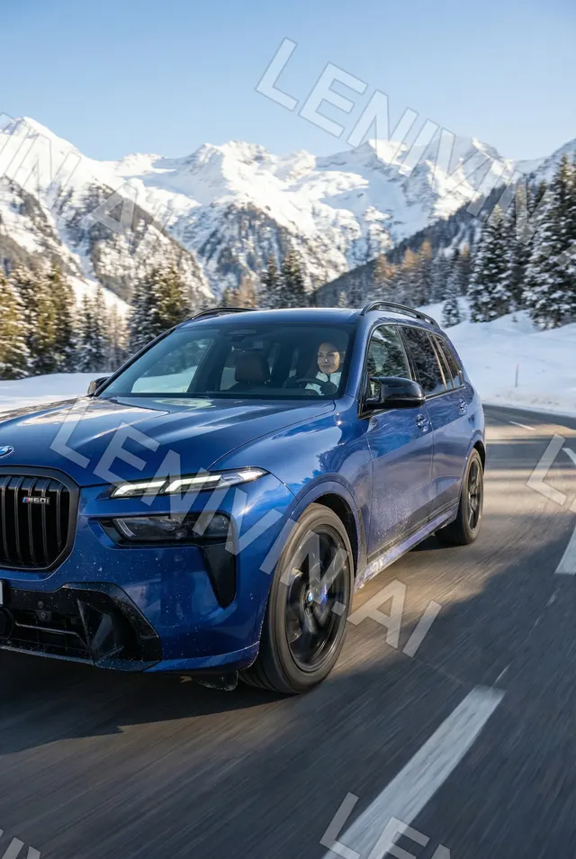 синий BMW внедорожник едет по заснеженной горной дороге, вдали снежные вершины