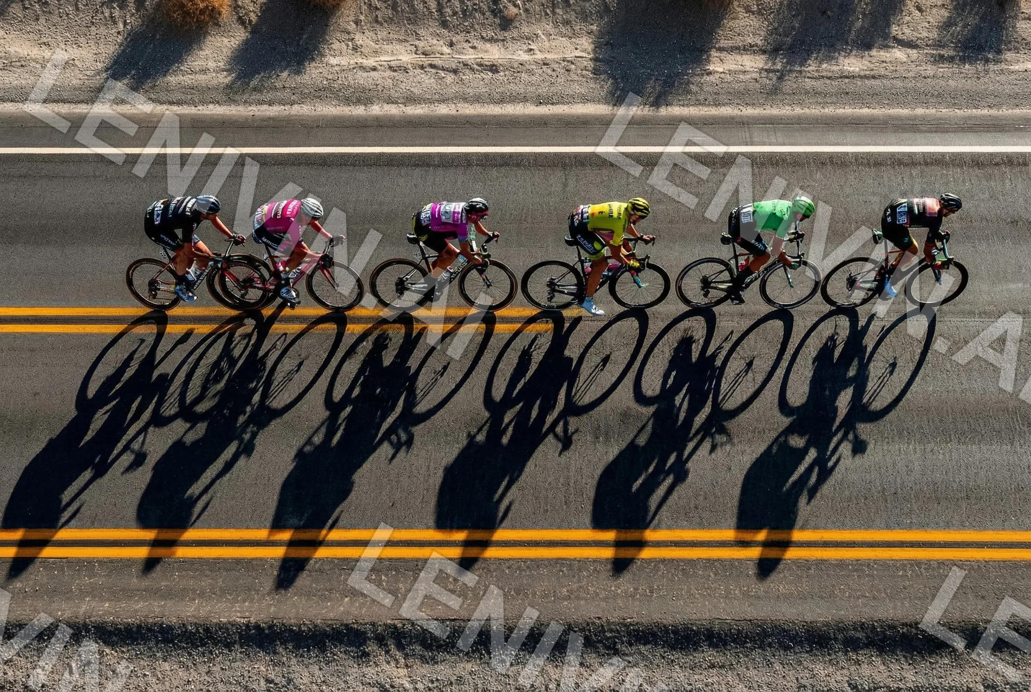 Шесть велосипедистов едут по дороге, длинные тени на асфальте, вид сверху