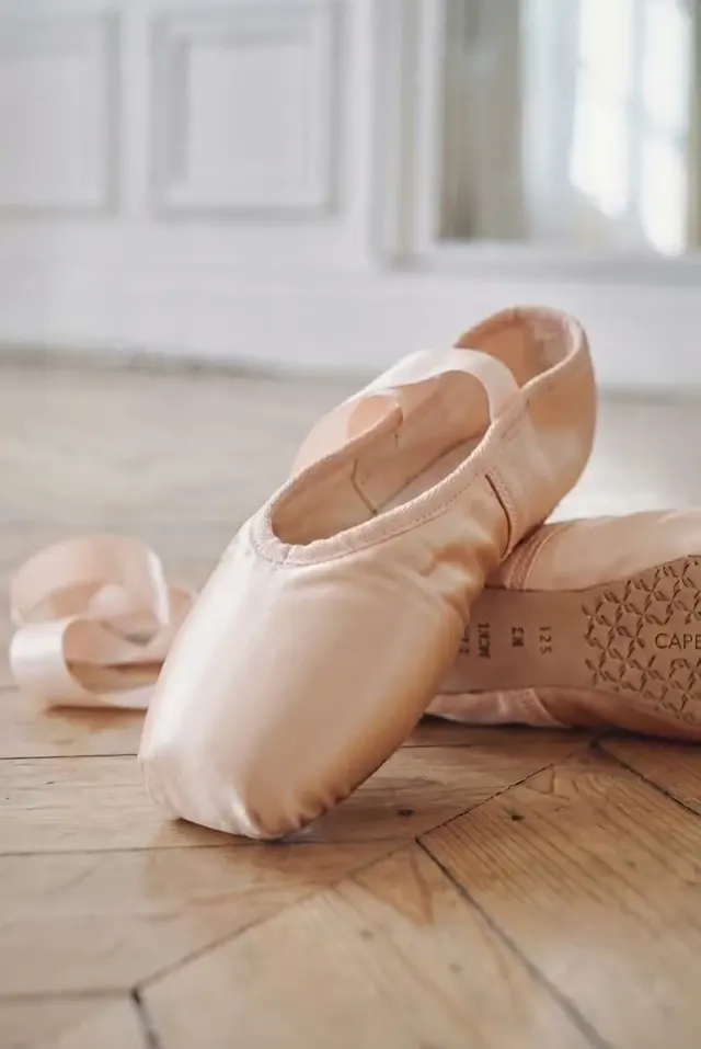 Ролик: персиковые пуанты Capezio с лентами на паркетном полу светлого зала